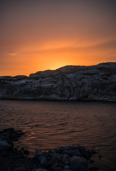 日落时湖边的褐色岩石山